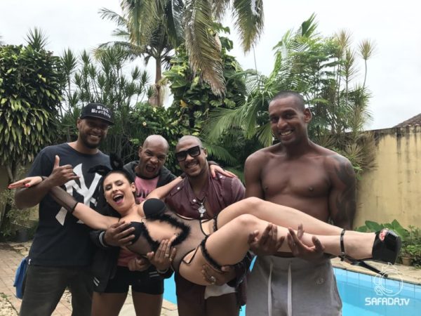 Emme White carregada por quatro atores à beira de uma piscina