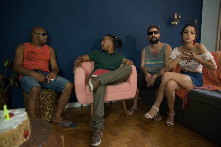 Elenco posa para a foto de divulgação numa sala de parede azul