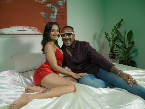 Casal conversa sentado numa cama de lençol de cetim